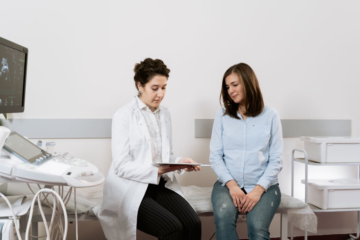 A gynecologist in a warm consultation, listening attentively to a woman patient
